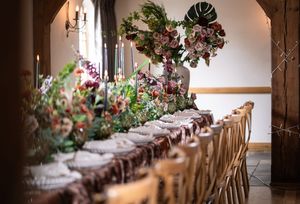 Elegant wedding reception table adorned with lush floral arrangements, candles, and fine tableware in a rustic venue.
