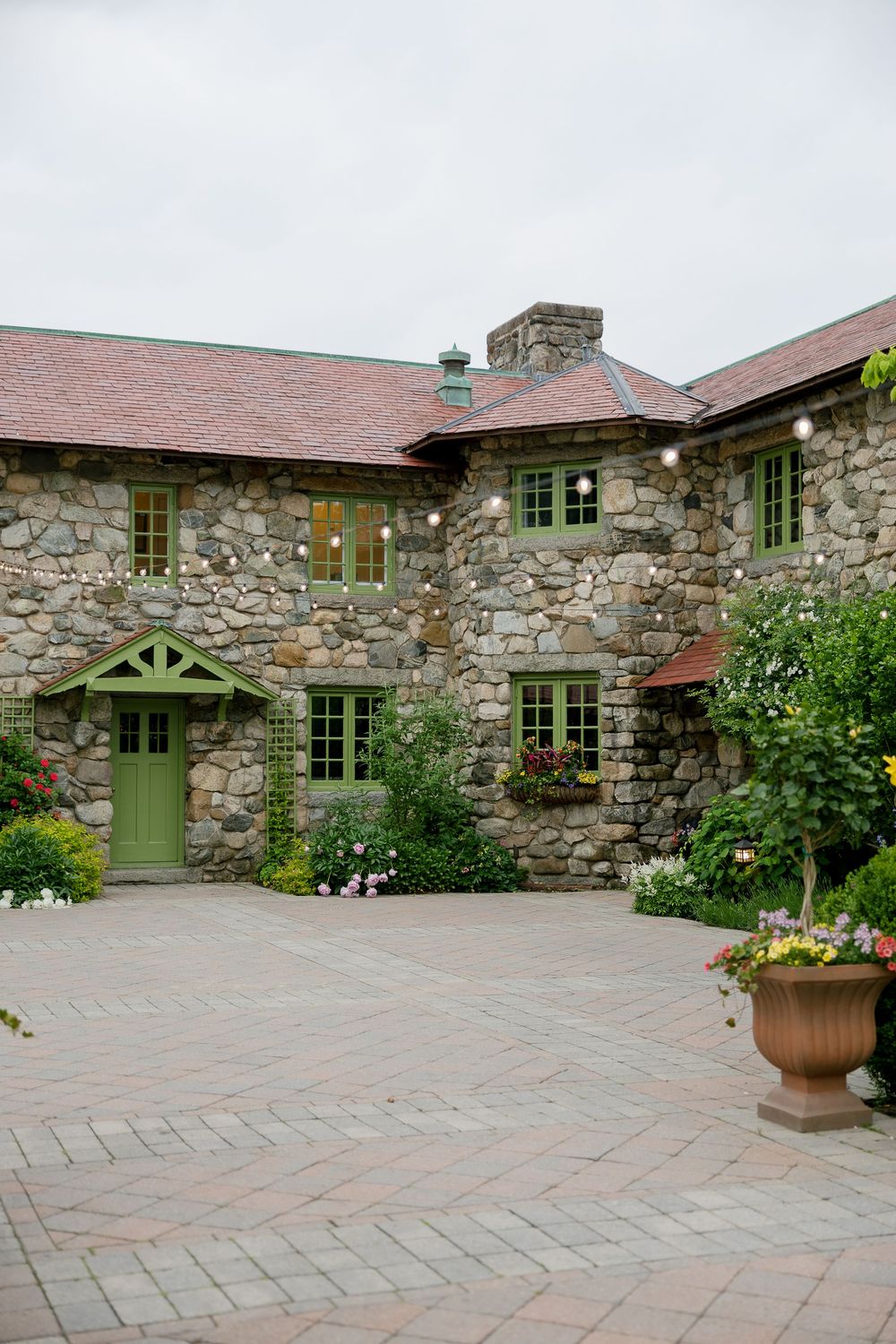 Charming stone cottage venue with green doors and windows surrounded by lush garden landscaping.