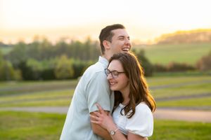 A joyful couple laughing together in an outdoor setting during golden hour.