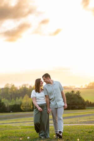 A couple walking together at sunset in a grassy field.