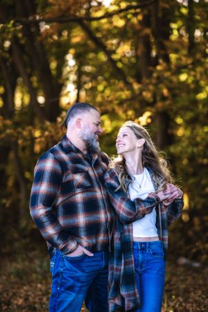 Couple in matching plaid flannel shirts share intimate moment in autumn woods.