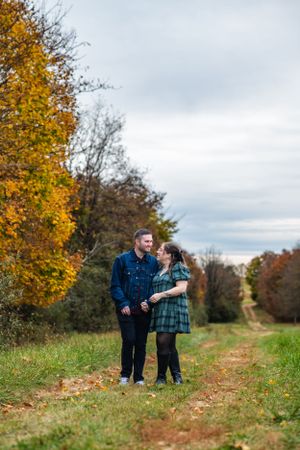 Couple walking together on path surrounded by fall foliage and colorful autumn trees.