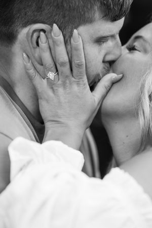 Close-up black and white photo showcasing engagement ring during intimate moment.