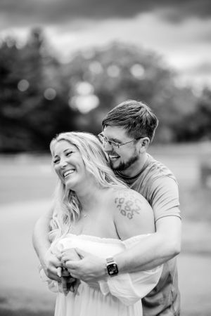 Black and white candid portrait of couple sharing intimate moment outdoors.