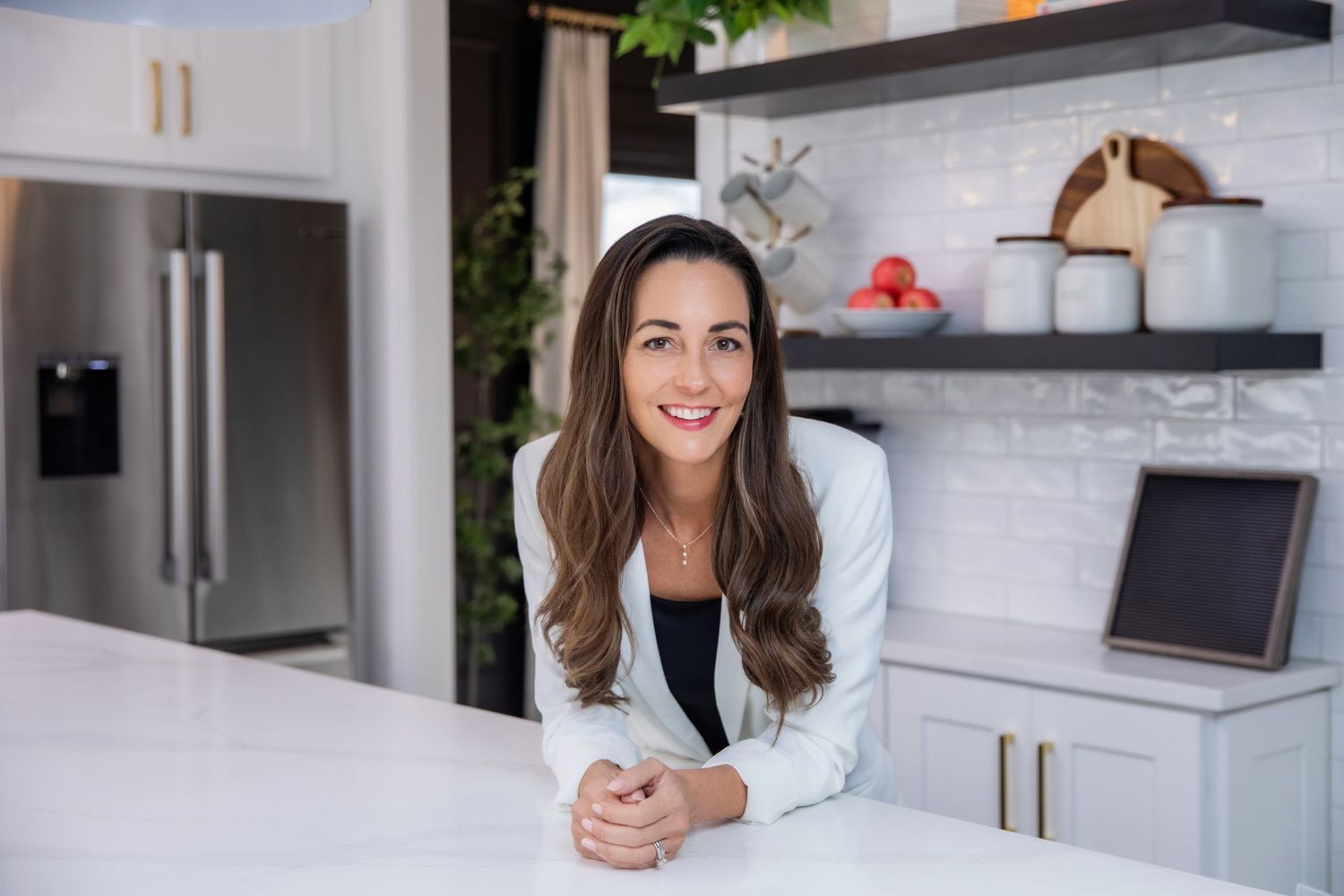 Real estate branding photo session in modern kitchen interior with white cabinetry and stainless steel appliances.