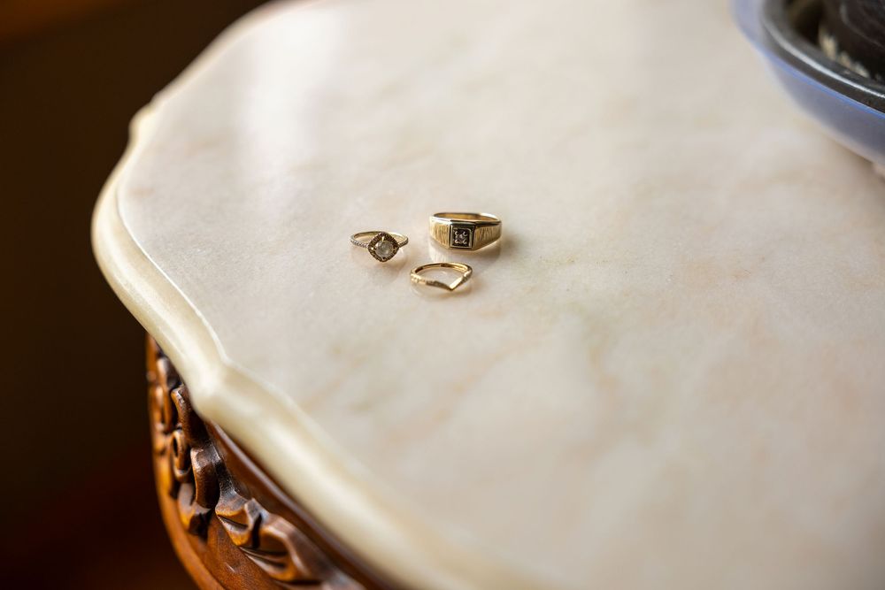 Close-up of two gold wedding rings resting on a marble table surface.