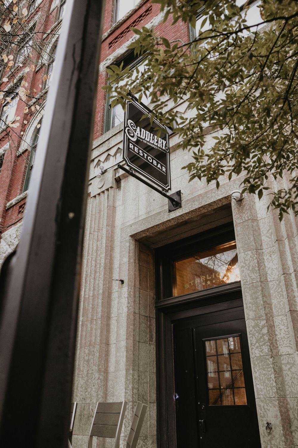 Exterior entrance of Saddlery Restored wedding venue with a vintage sign framed by brick and stone architecture.