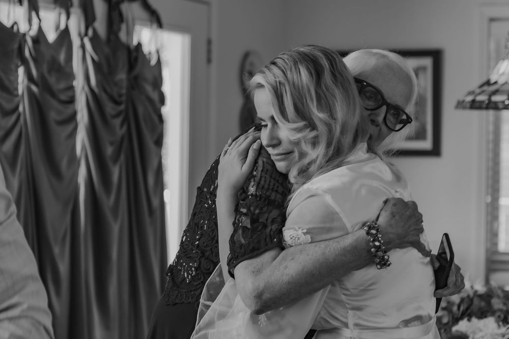 Emotional black and white photo of two women sharing a heartfelt hug during wedding preparations.