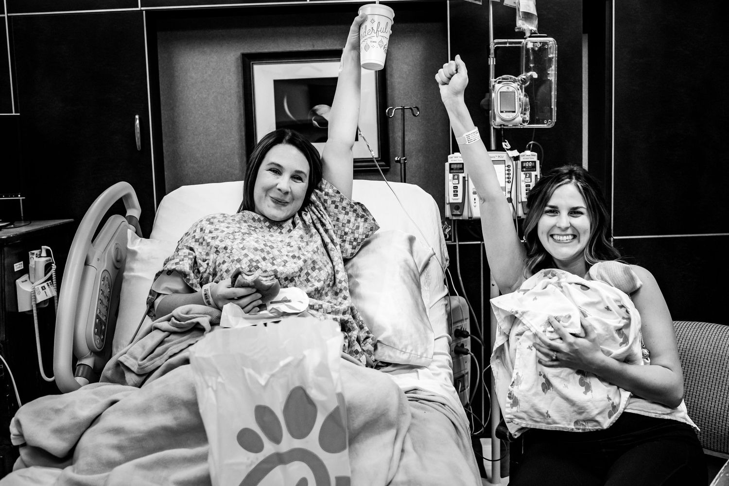 Black and white hospital photo captures joy and celebration with a newborn baby.