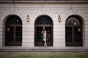 Woman in colorful dress posing before grand arched stone building entrance with ornate lanterns.