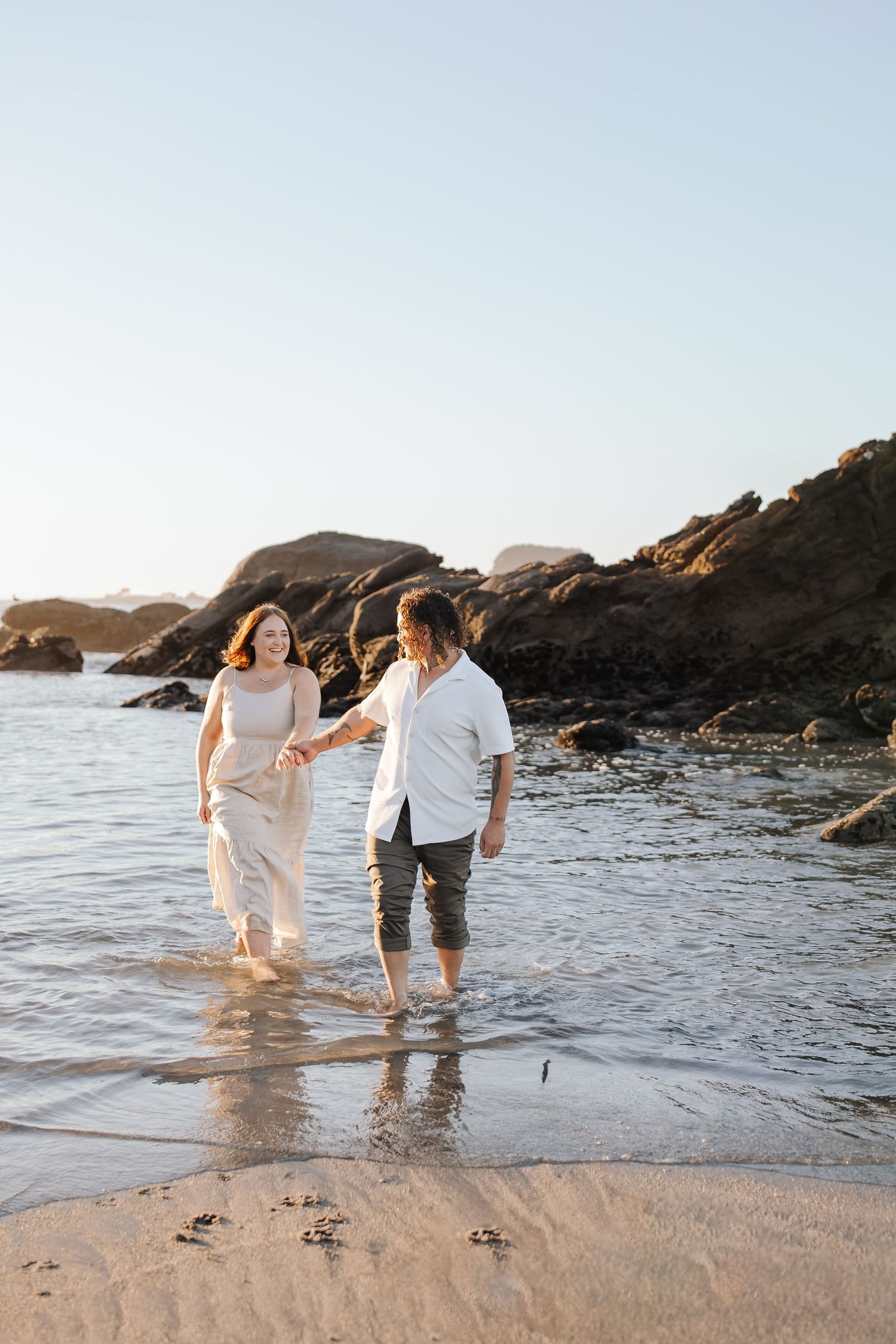 Bride and groom holding hands on a rugged West Coast NZ beach