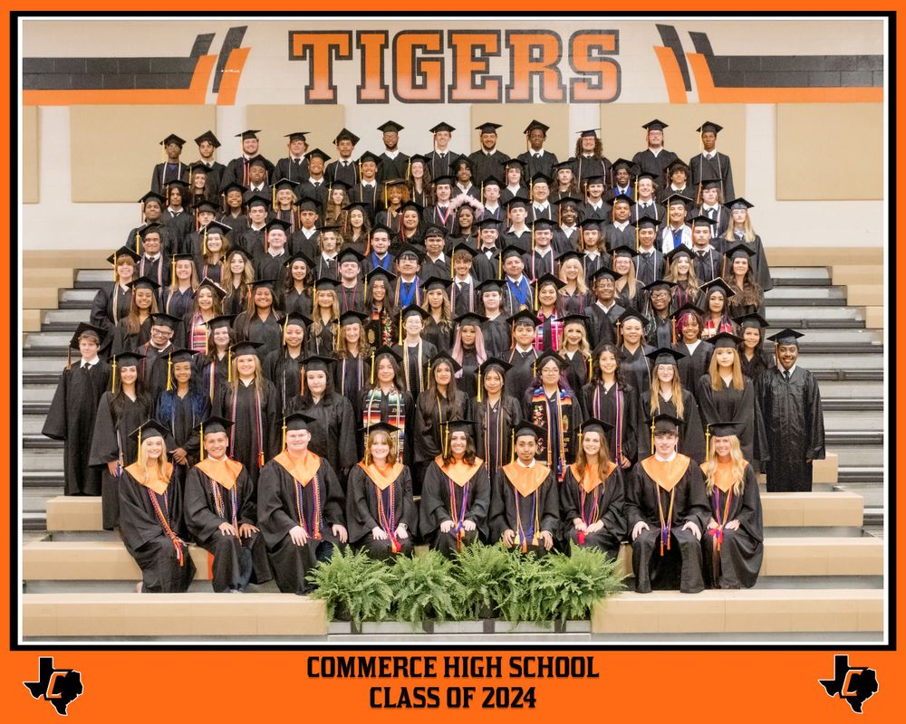 A large group of graduates in black caps and gowns pose on stairs under a Tigers banner for a class photo.