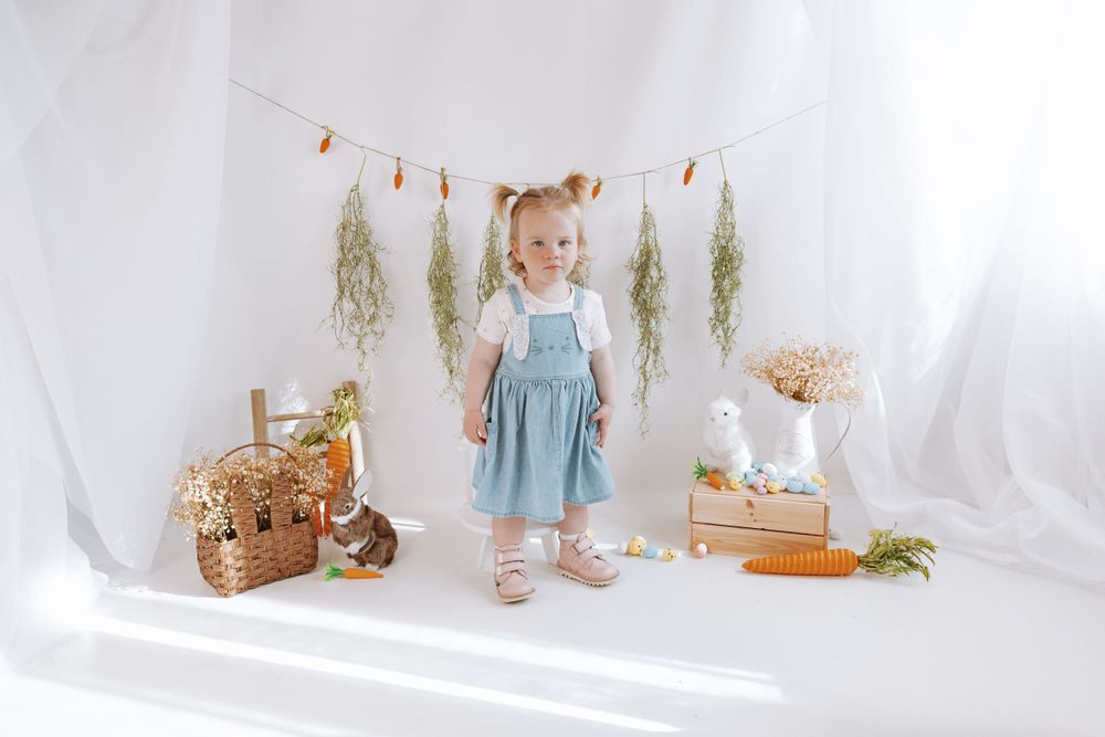 Light and airy styled photo setup with vintage basket, dried flowers, and soft white draping fabric in natural sunlight.