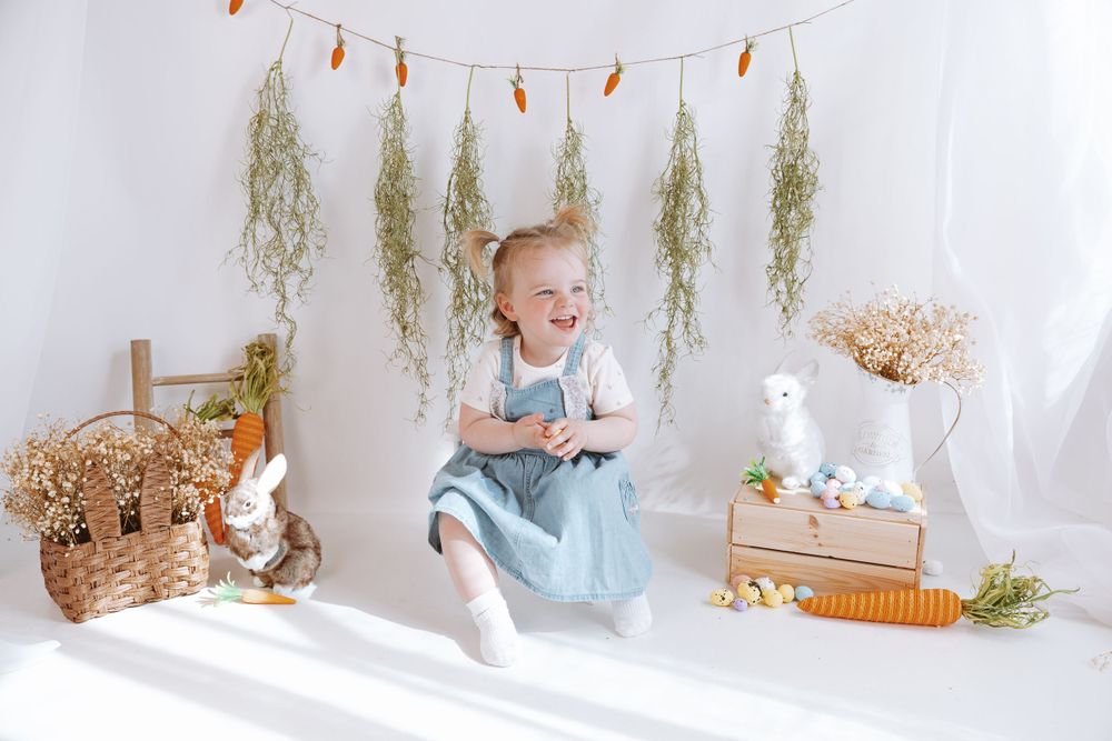 A charming Easter setup with hanging dried herbs, wicker basket, bunny decor, and a joyful moment on white backdrop.