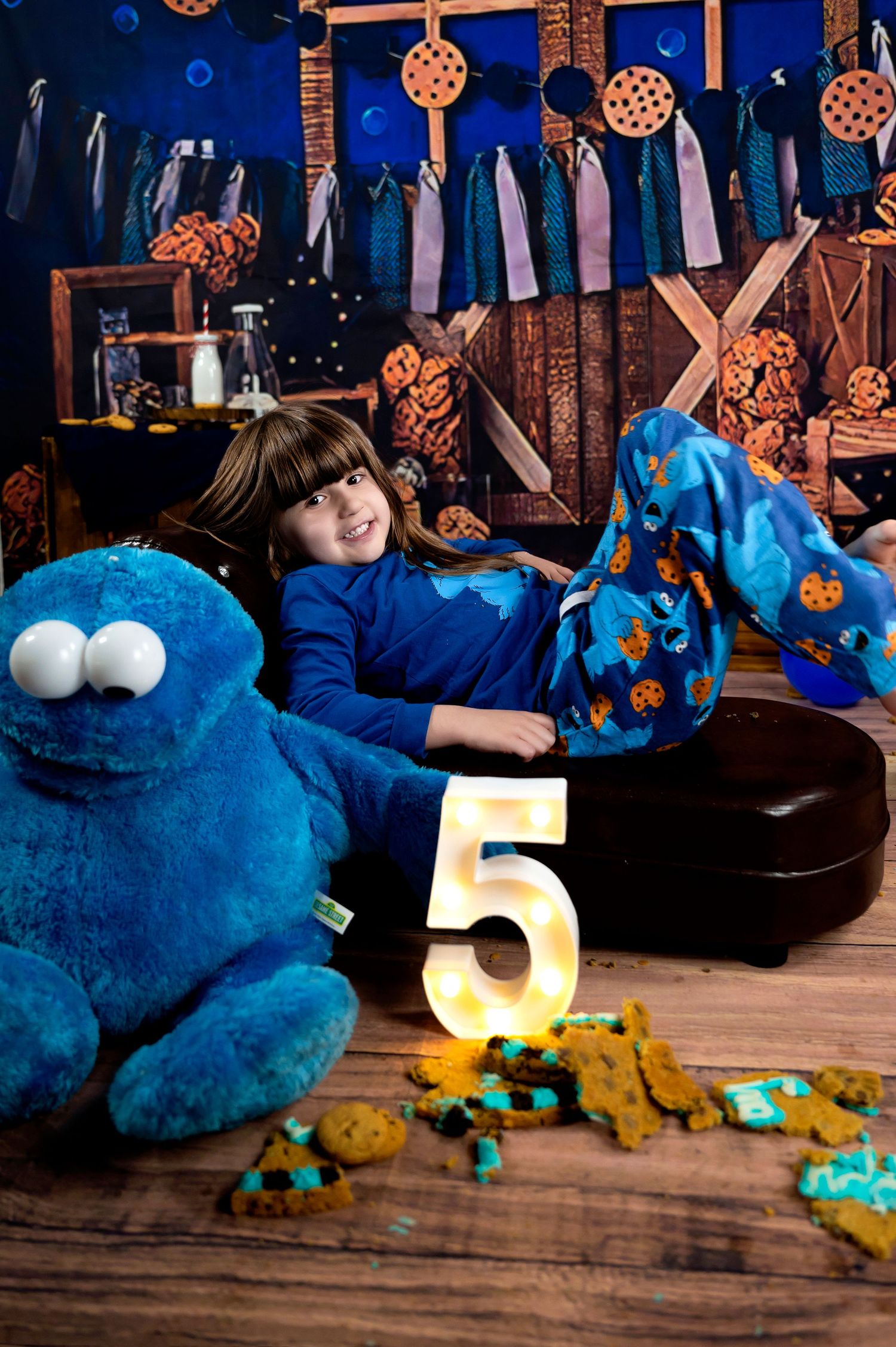 A baby in overalls sits on the floor engaged in finger painting with black paint, creating messy artwork.
