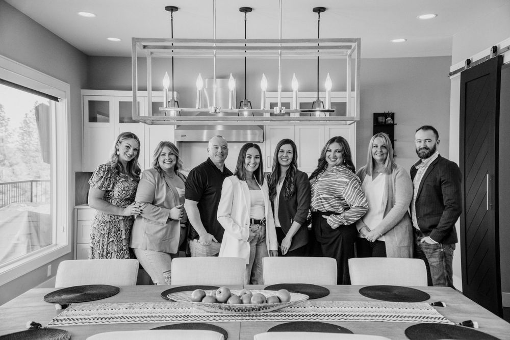 A group of professionals pose together in a modern kitchen with pendant lighting and a large island in black and white.