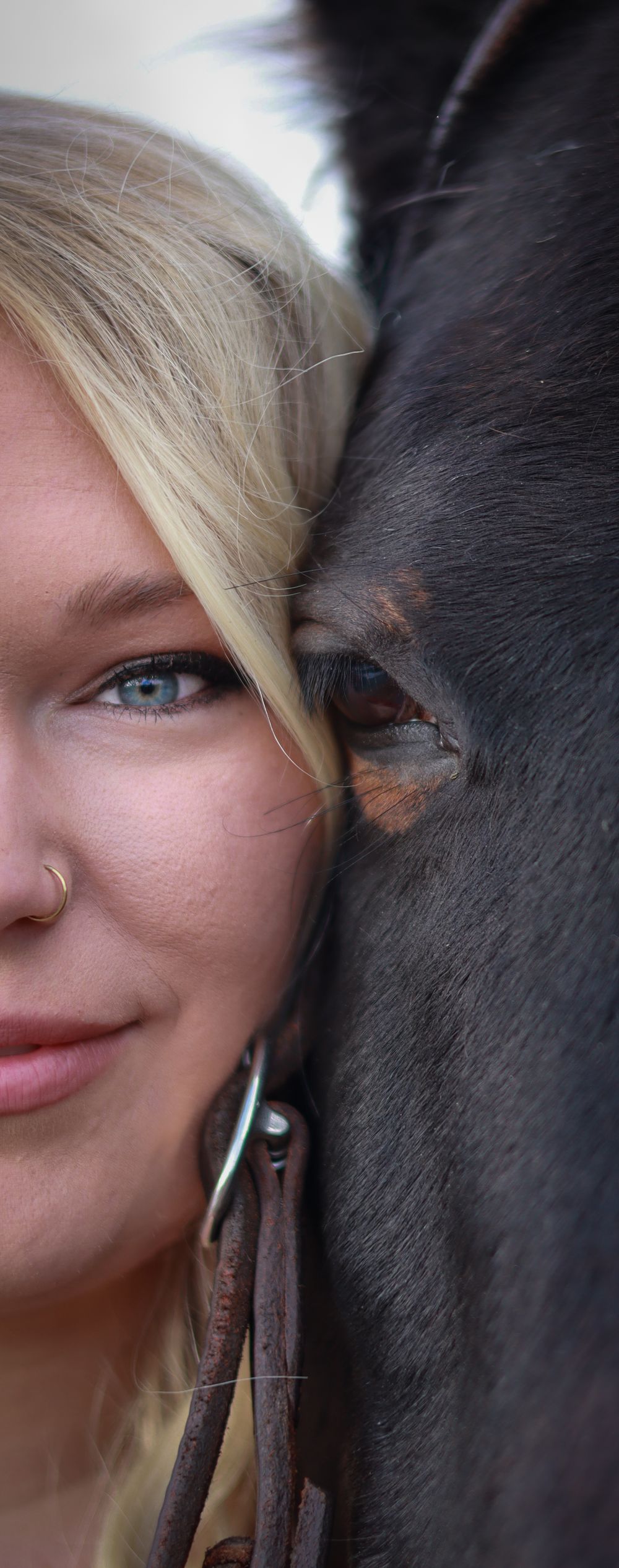Close up portrait showing half a face next to a dark horse's eye in an intimate pose.
