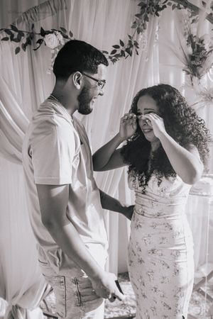 Black and white photos capture intimate moments between couple against white floral backdrop.