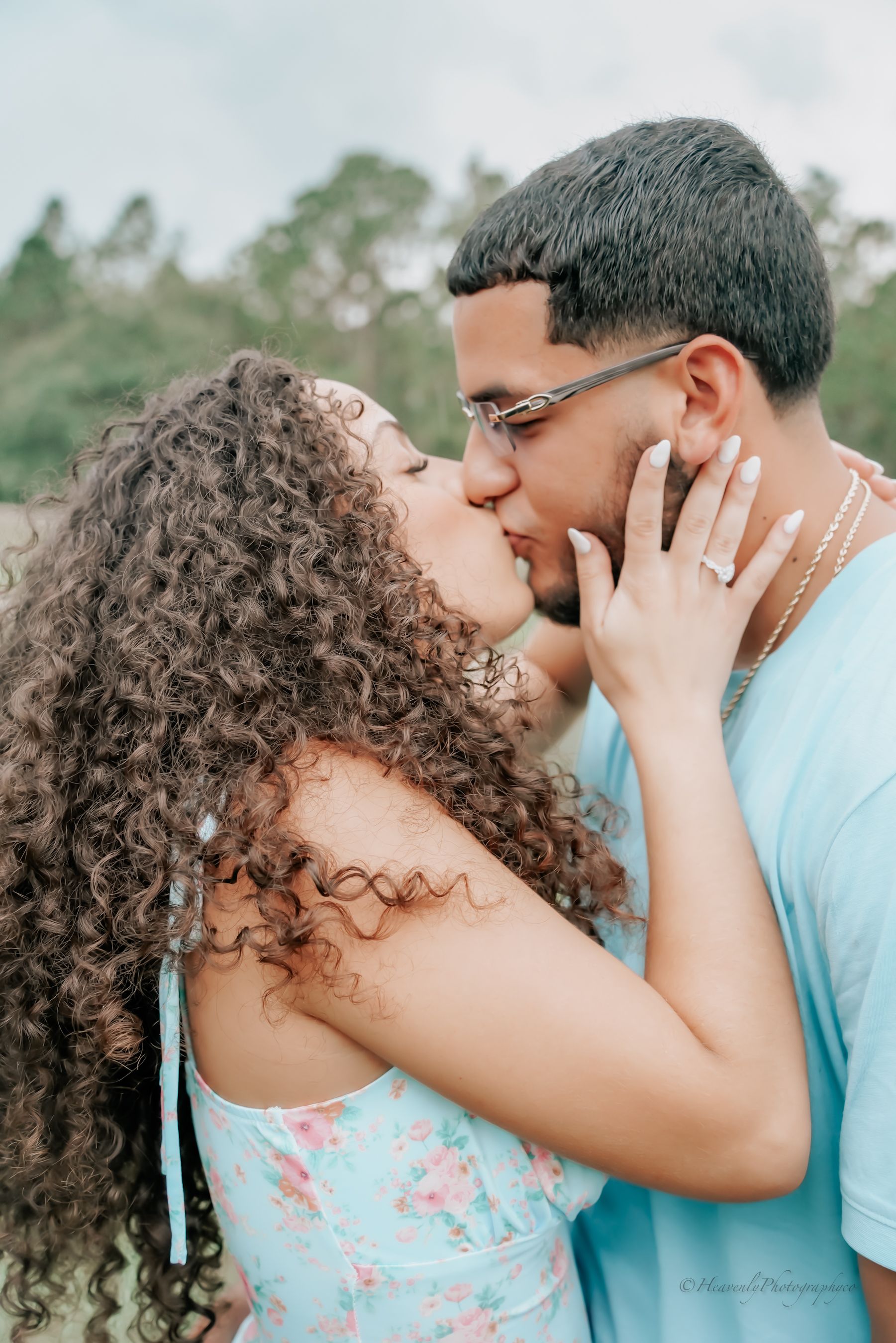 Romantic outdoor couple photo with natural lighting and trees in background.