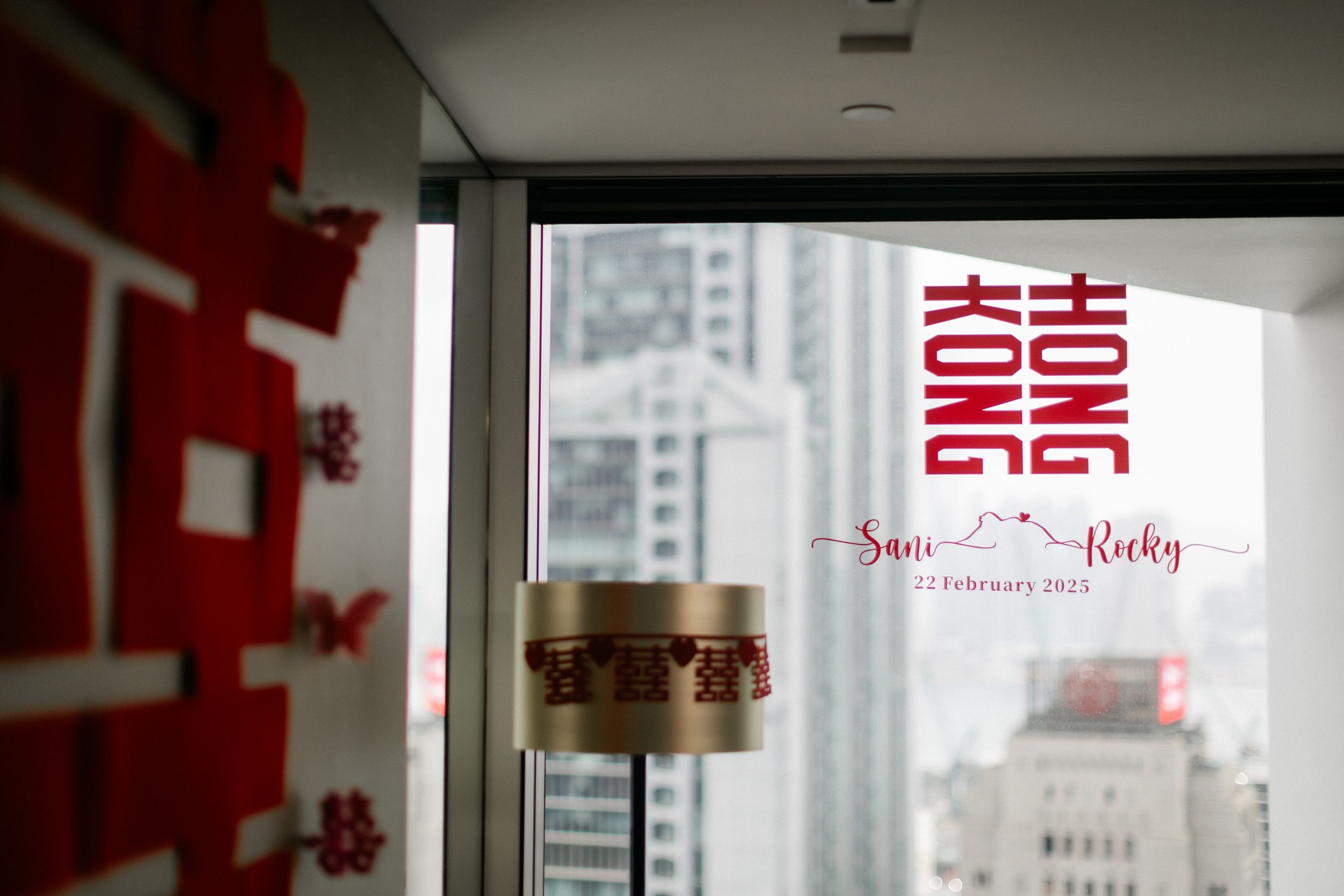 Hong Kong cityscape view through window with San Rocky wedding date neon sign decoration.