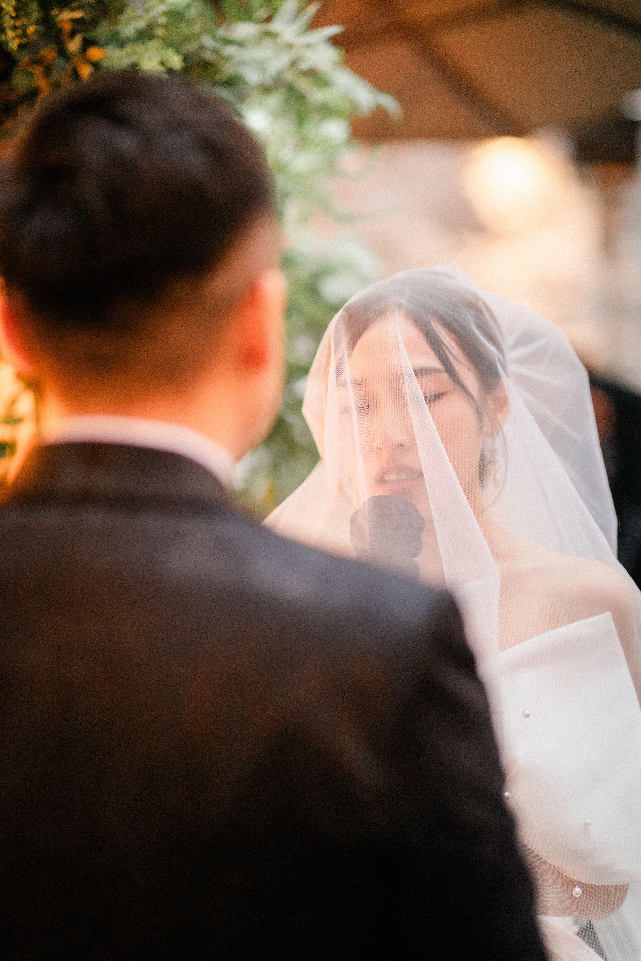 Close-up of a bride wearing a veil looking at her groom during their wedding ceremony.