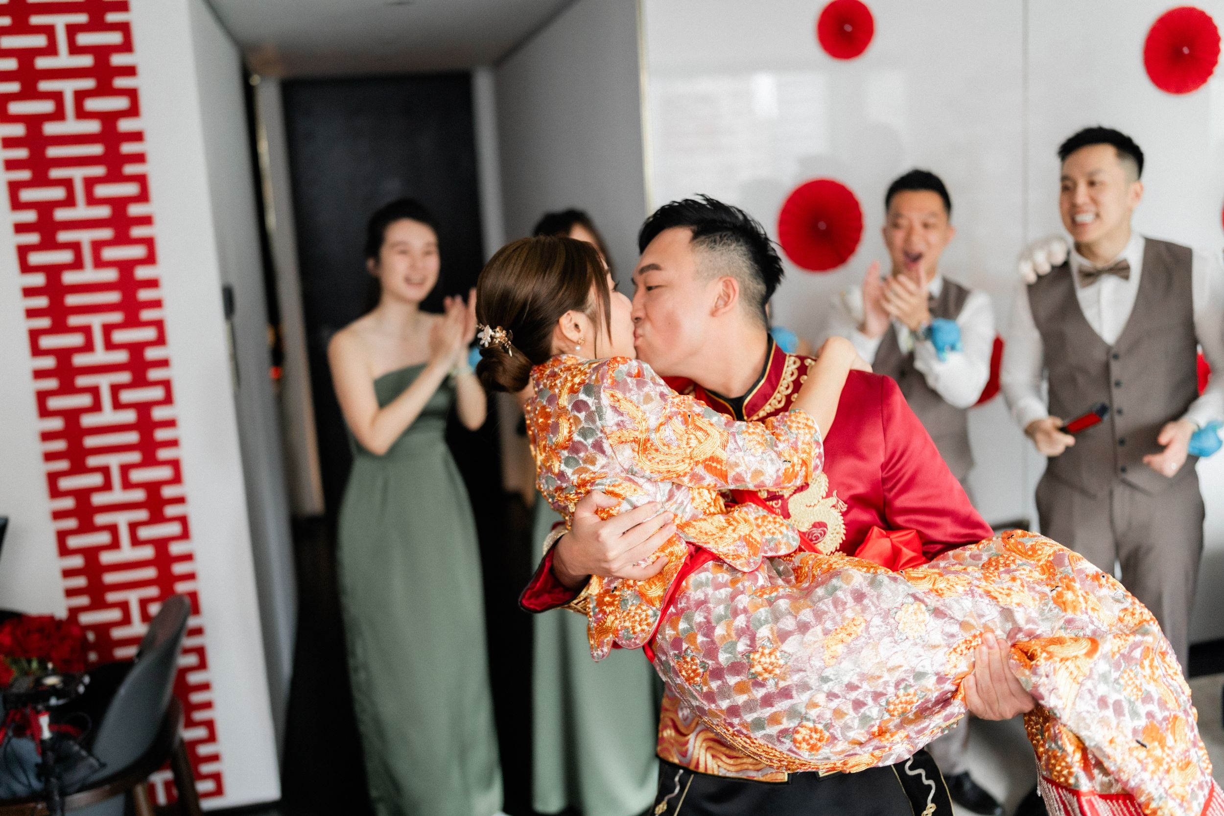 Groom sweeps bride off her feet with a kiss during traditional Chinese wedding celebration.