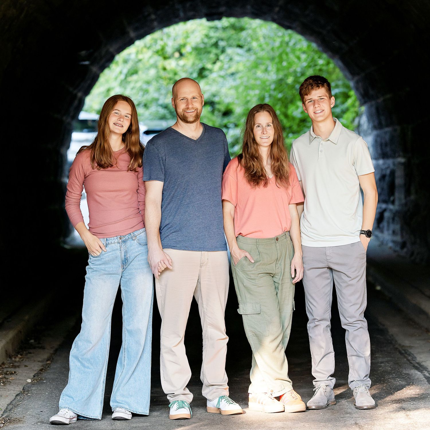Photo of a family standing in a tunnel during the summer taken by Milwaukee family photographer Rachel Dickman.