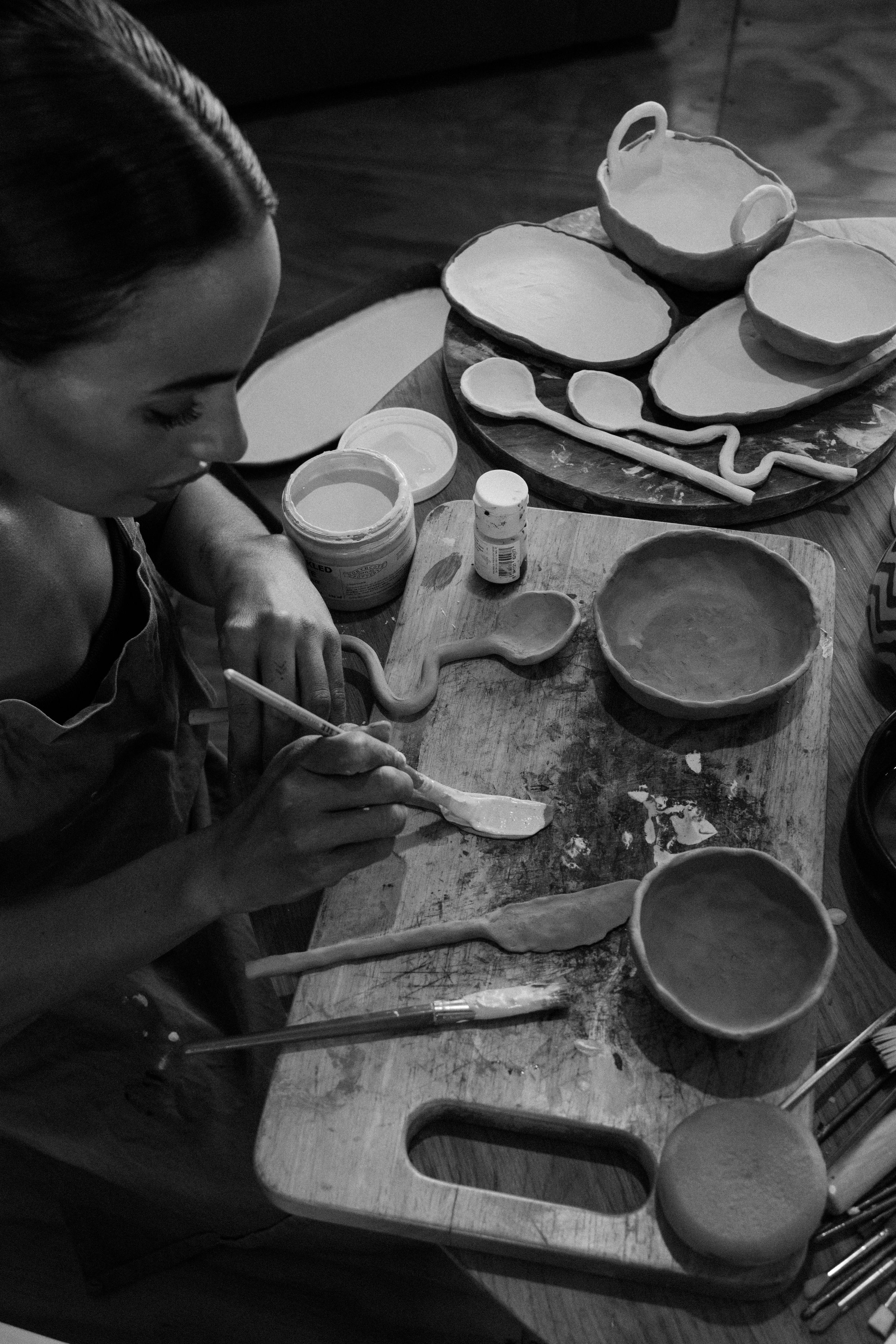 Artisan working on handmade pottery pieces in a black and white photograph.