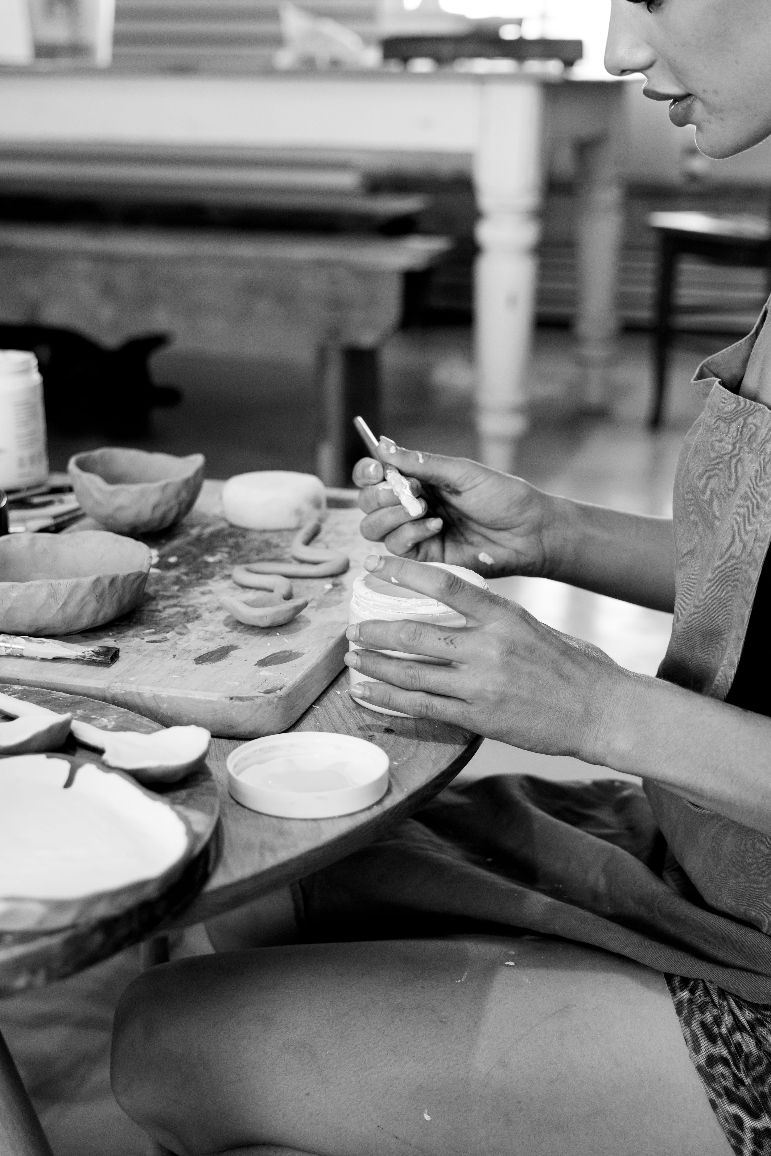 Close-up of hands crafting ceramic pottery on a wooden workbench.