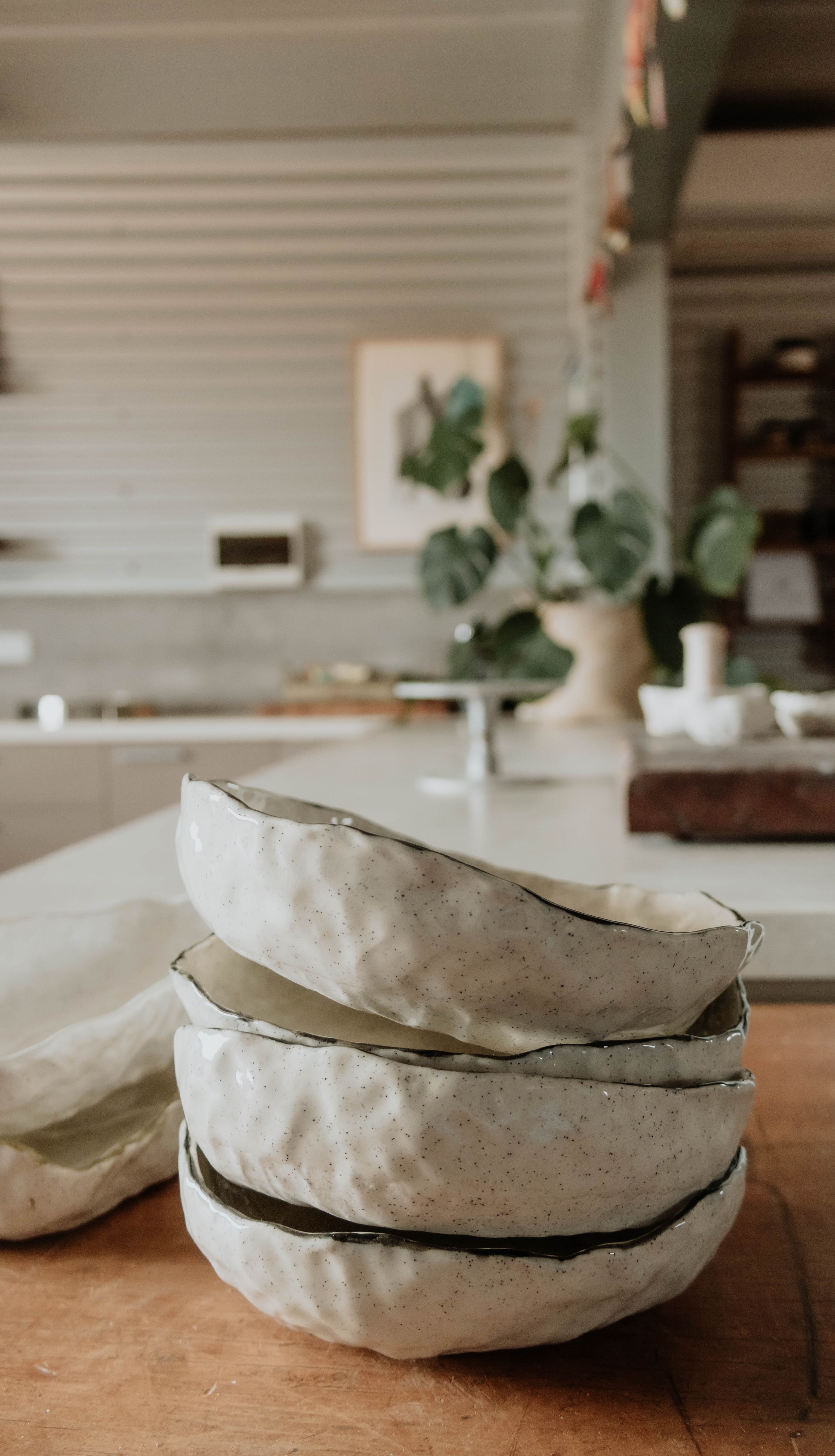 Stack of handmade ceramic bowls with organic textures on wooden surface.