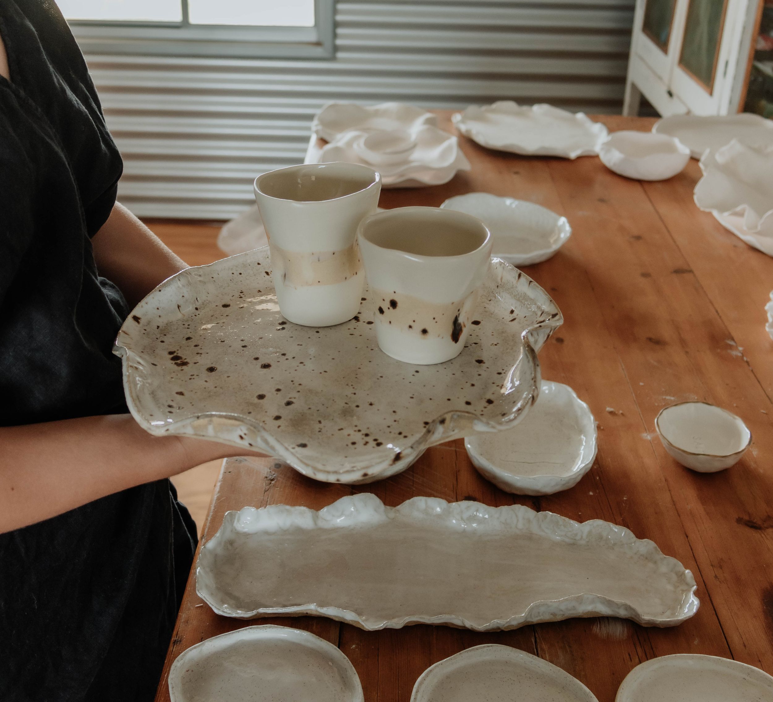 Handmade ceramic bowls and cups arranged on a wooden table surface.