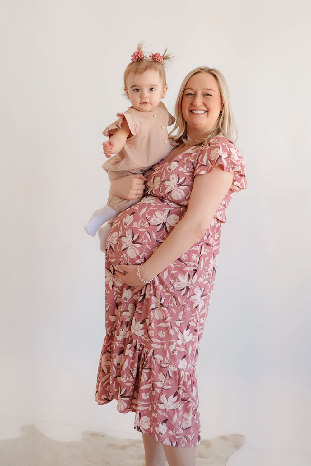 A sweet photoshoot featuring a pink floral dress and coordinating outfits against a light background.