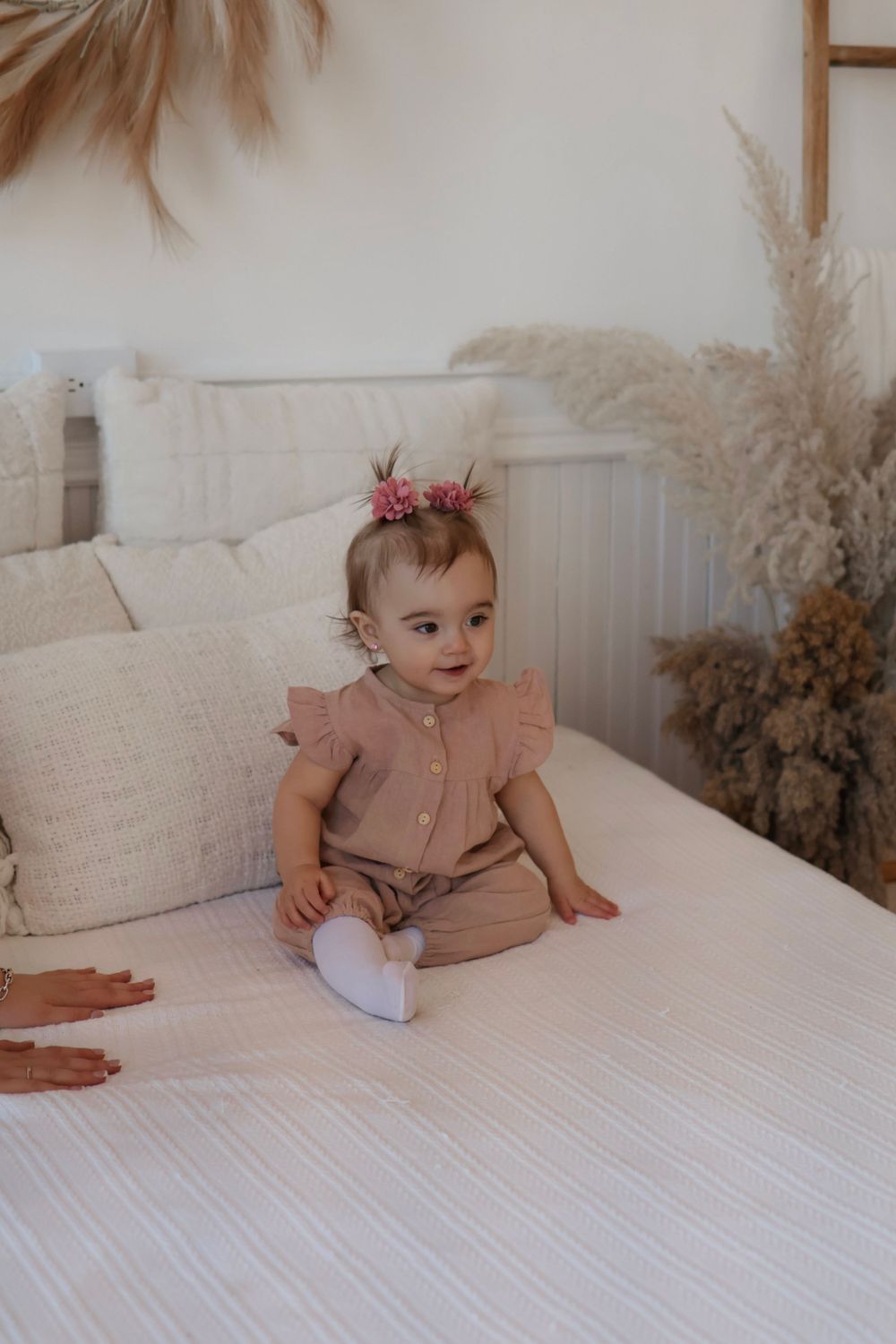 Natural light photography session on white bedding with neutral decor accents.