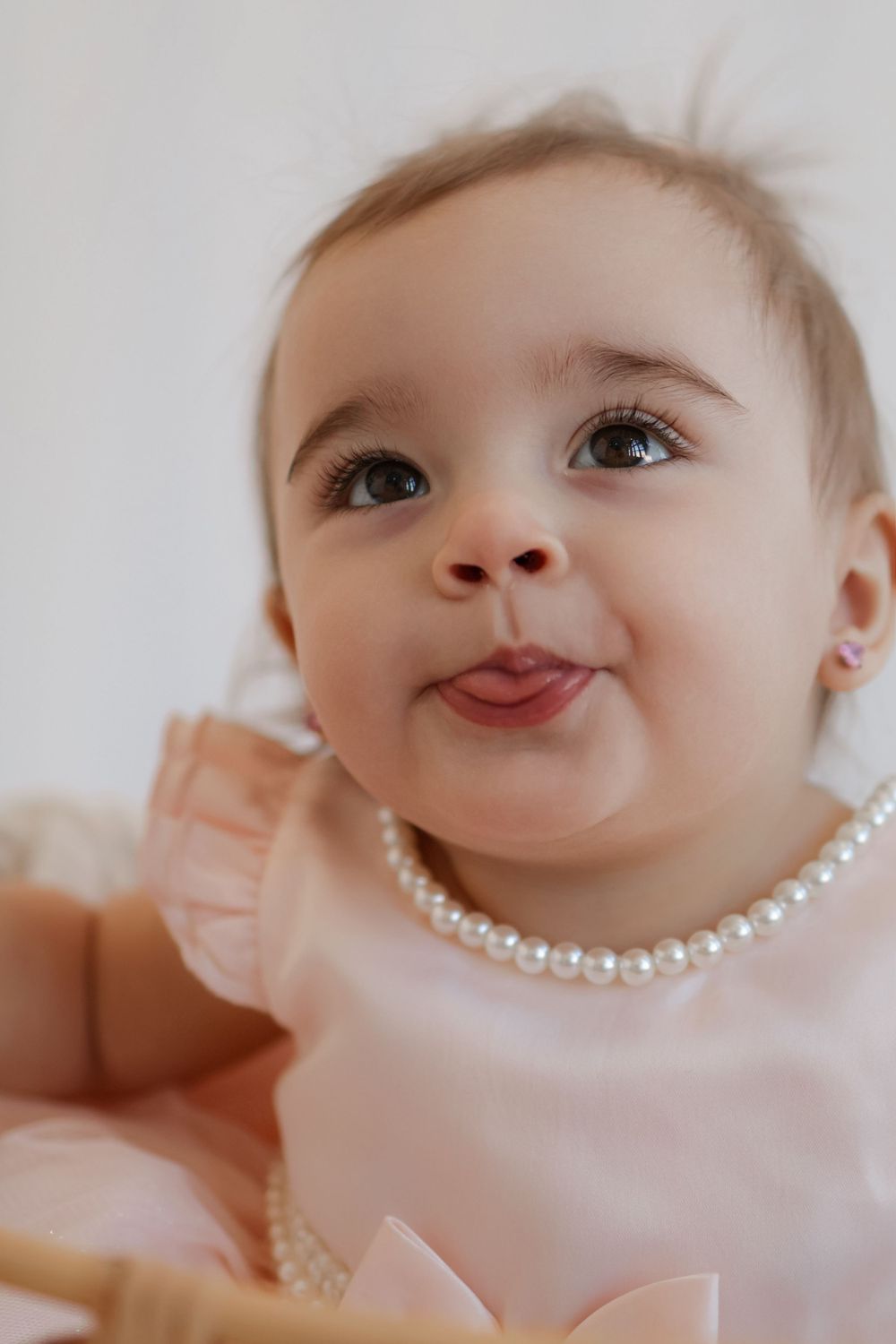 Close-up of baby wearing pearl necklace and pink dress.