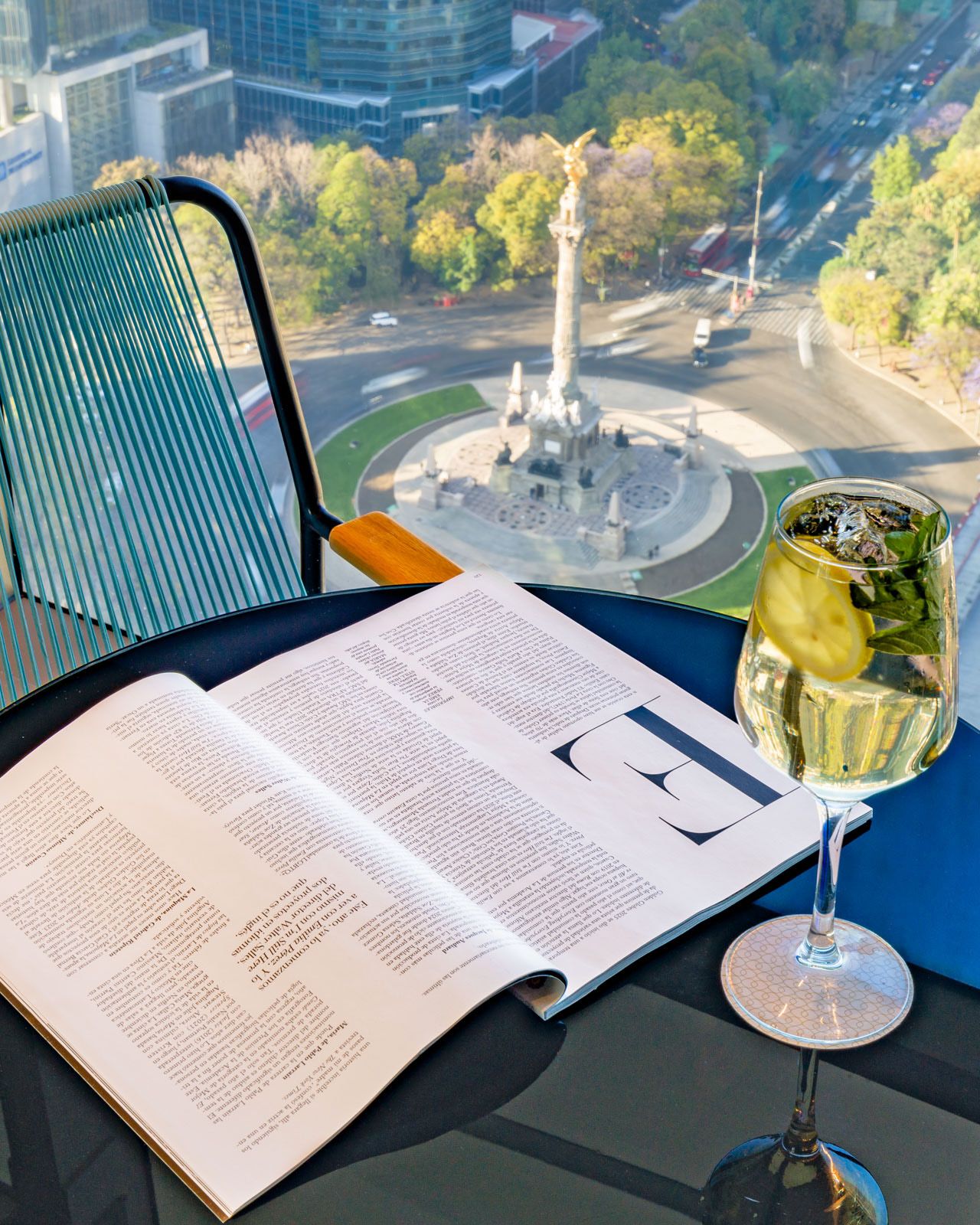 Aerial view from Sofitel Mexico City Reformra of Insurgentes Angel with open book and coctail in foreground.