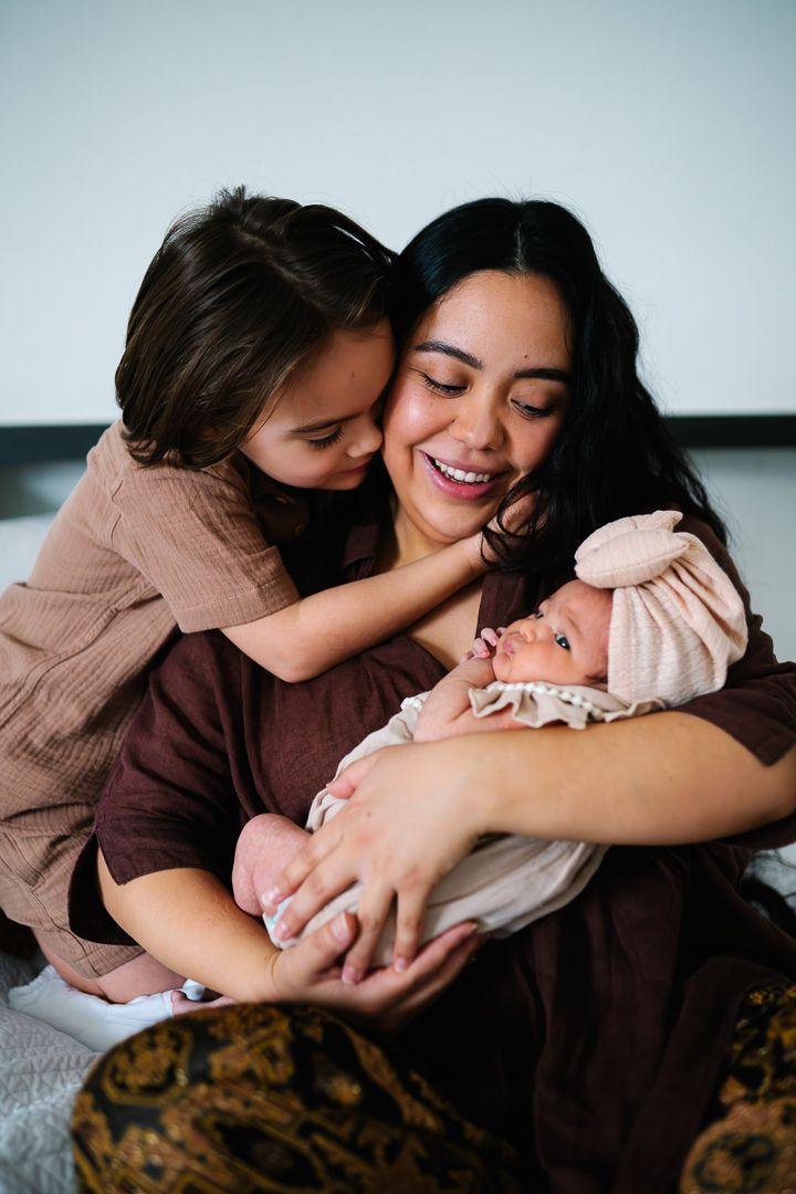 Mother cradling her newborn with her son during a newborn photoshoot at home by Melbourne newborn and family photographer Pei A Photography