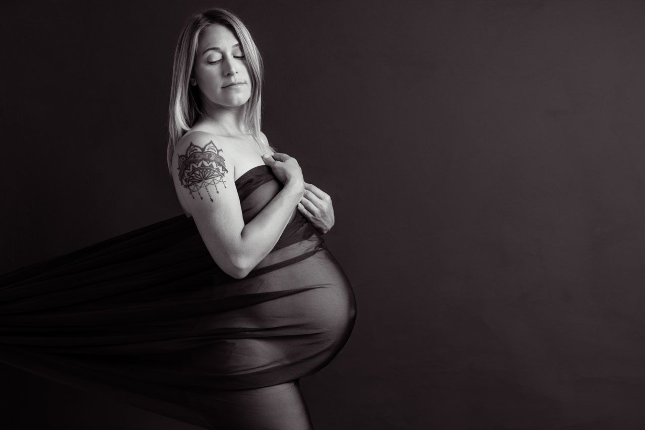 Timeless black and white maternity portrait of a mother-to-be wrapped in fabric in a North Auckland photography studio