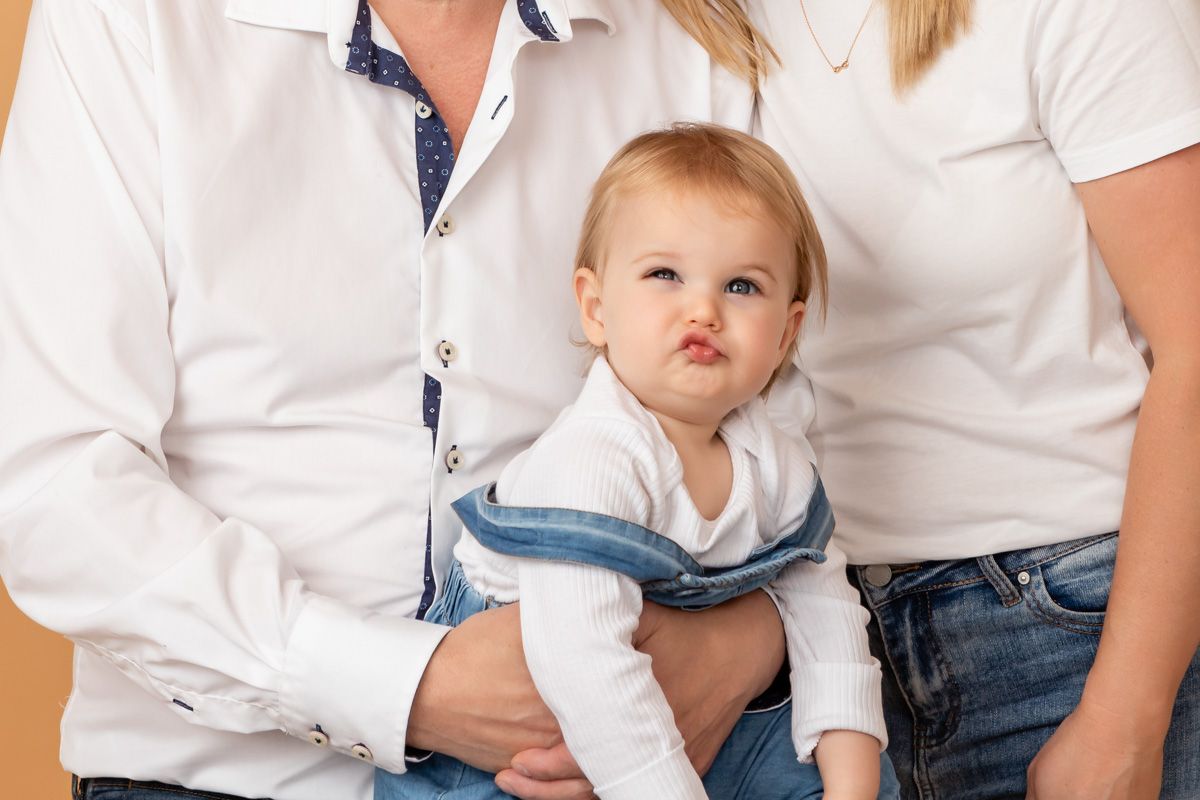 one year old girl pulling funny face at her cake smash photoshoot.