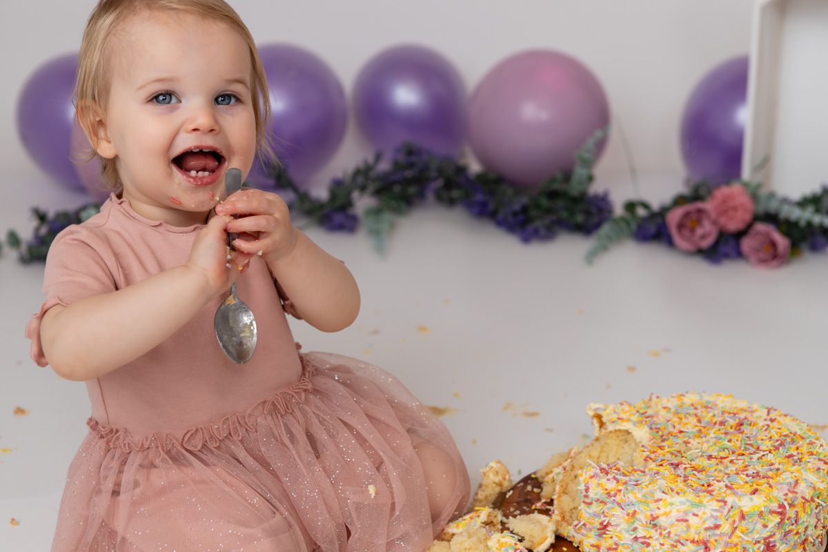 Smiling baby celebrating first birthday during a cake smash photoshoot.”