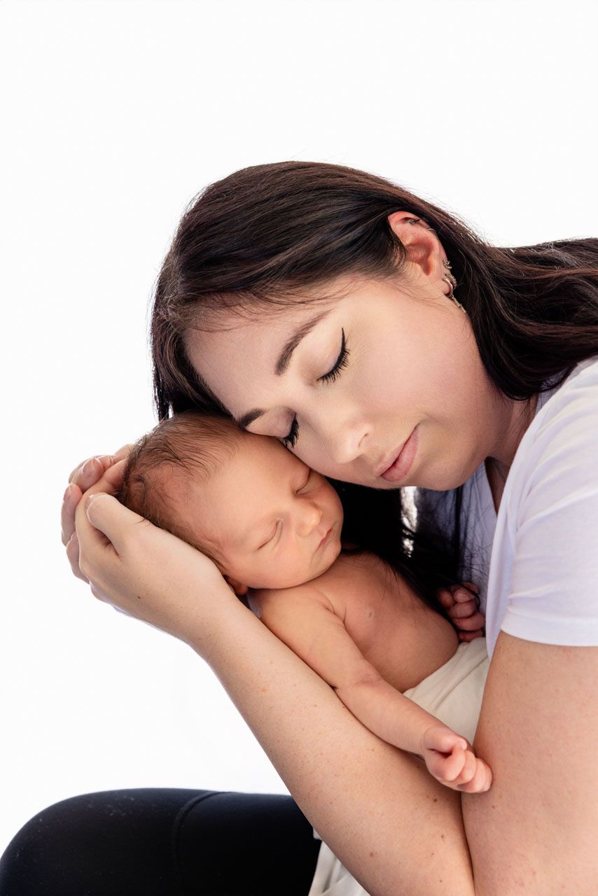 Baby boy portrait, wrapped in white having cuddles with Mum