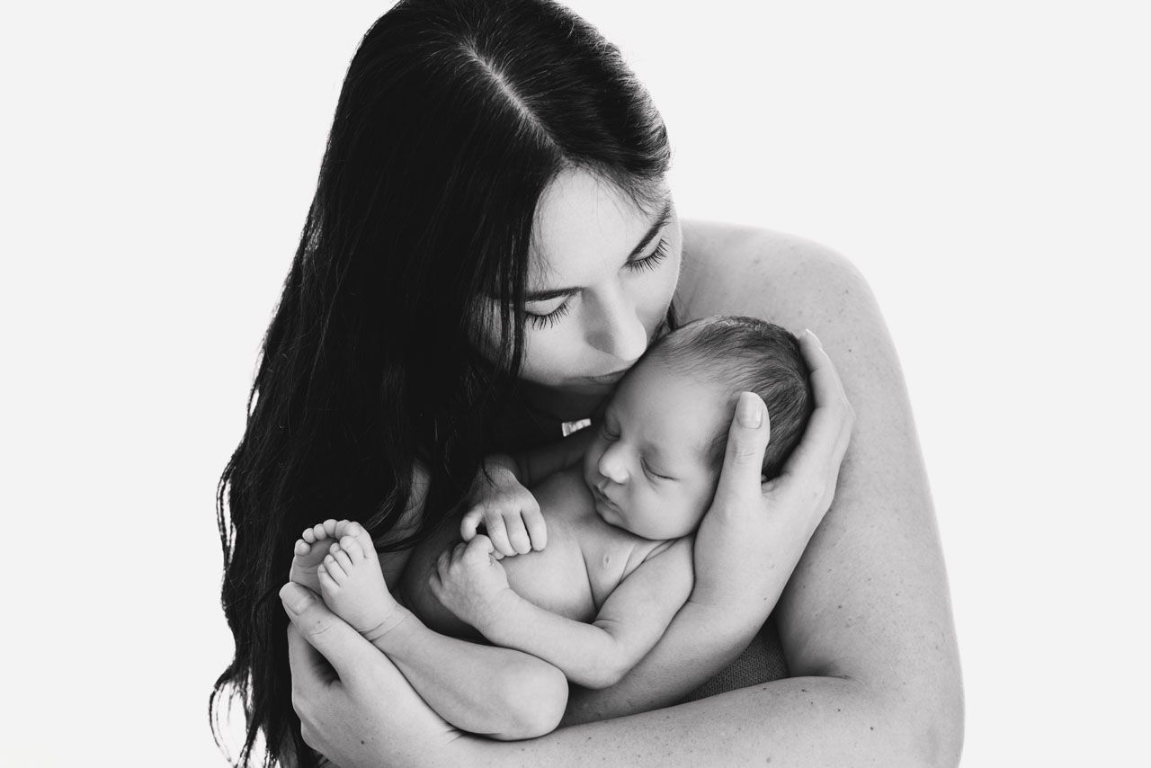 kin‑to‑skin connection – mum holding newborn against her chest black and white