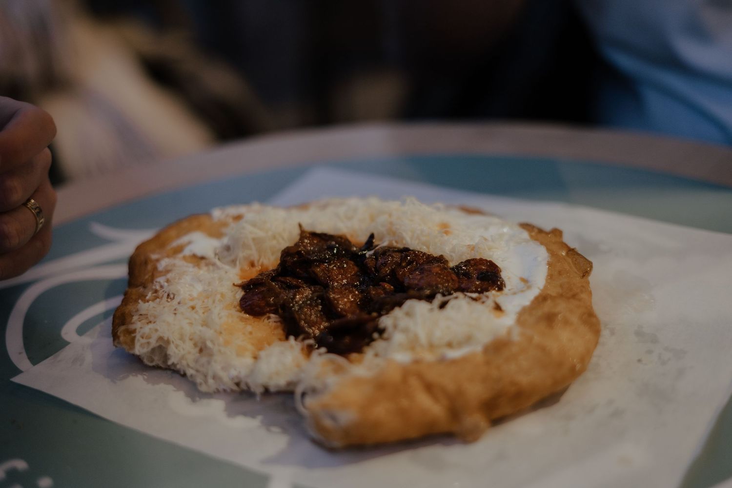 A savory meat dish served on a white plate with rice and crispy flatbread.