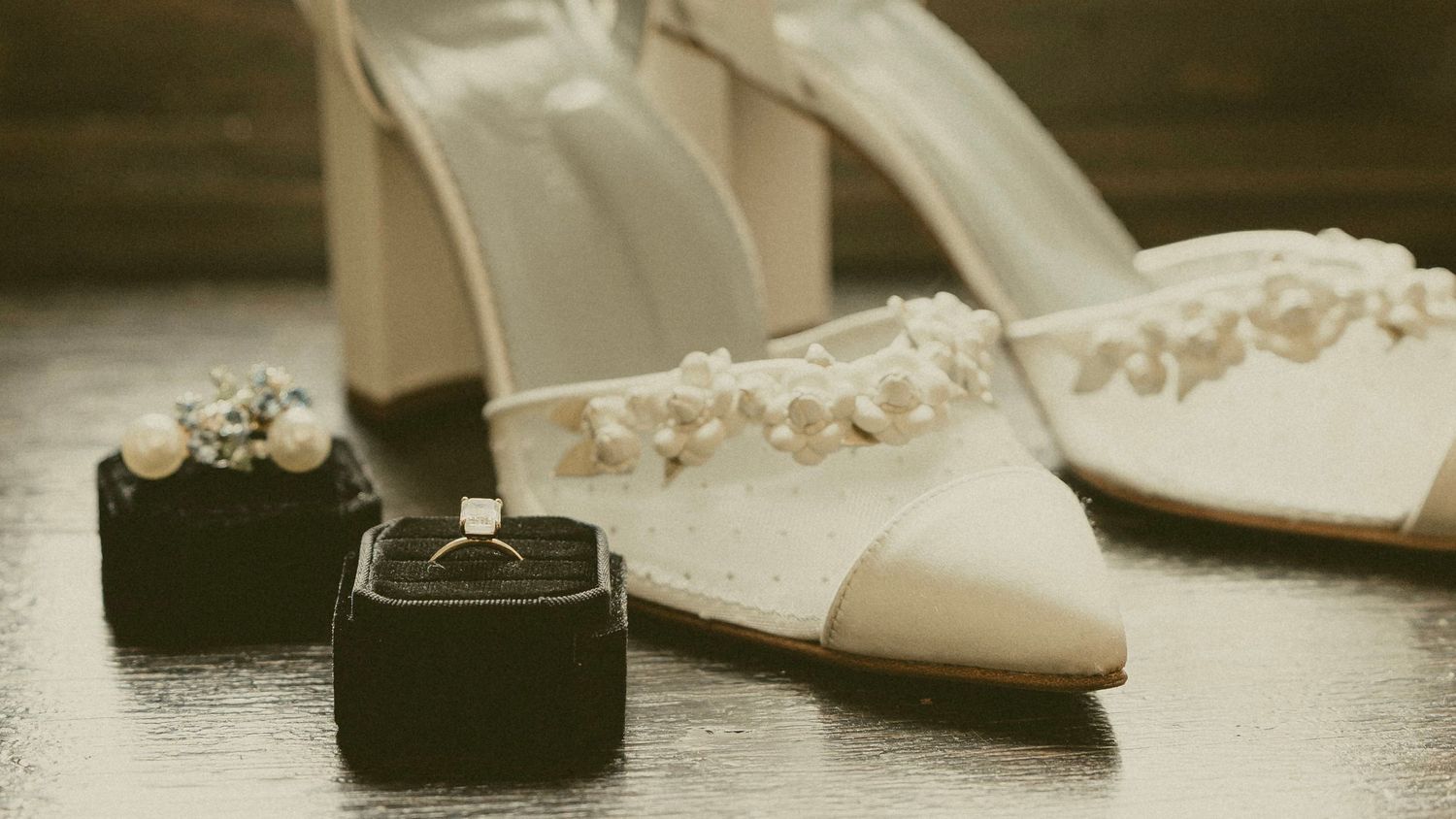 Elegant white bridal shoes and wedding rings in black velvet boxes on light surface. Cincinnati Ohio.