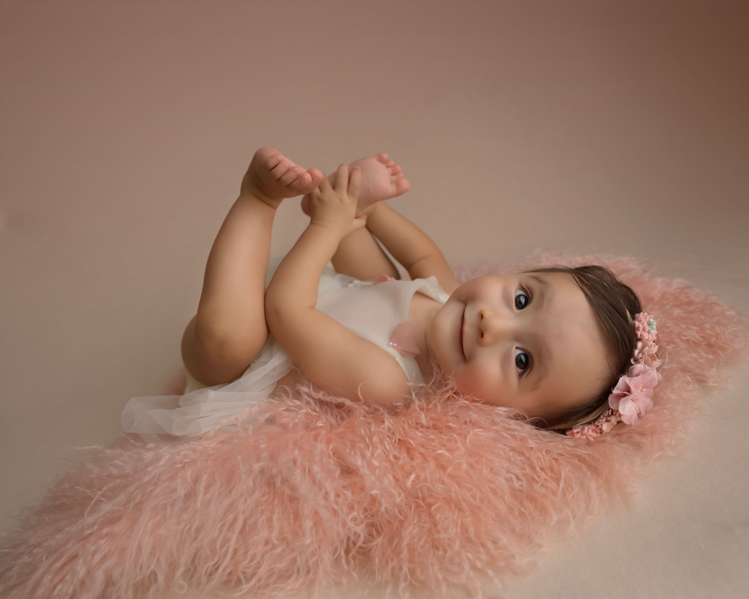 Baby photography session featuring soft pink textured backdrop.