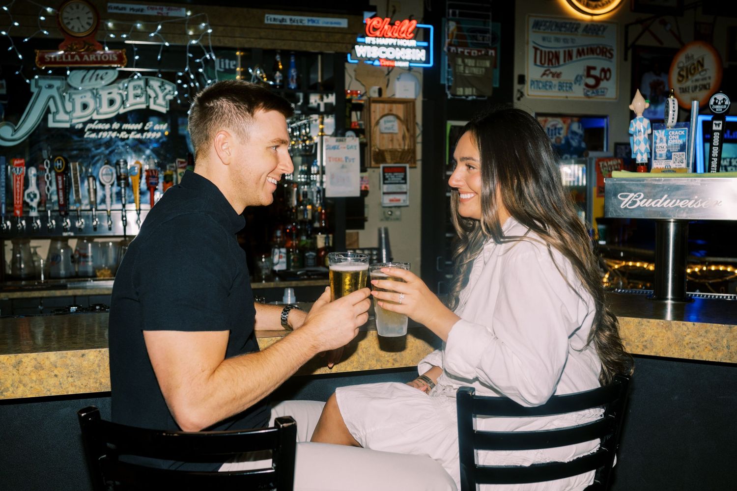 Two people enjoying drinks together at a bar counter in a casual evening setting.