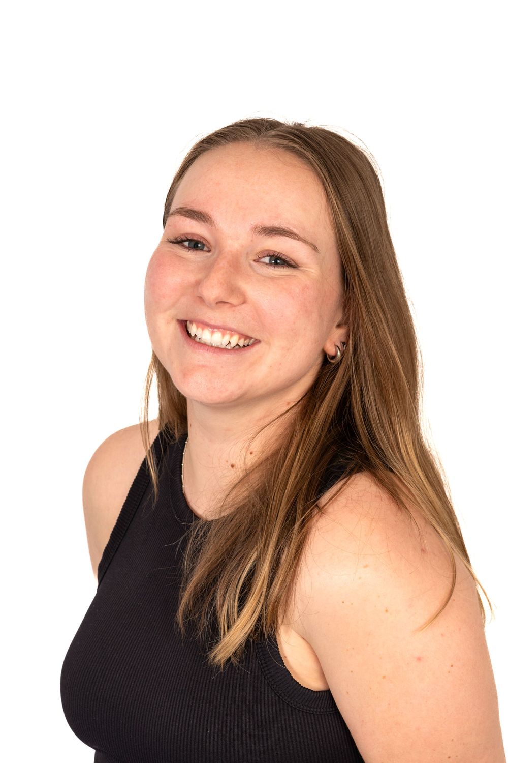 Smiling young woman with long brown hair wearing a black sleeveless top against a white background.