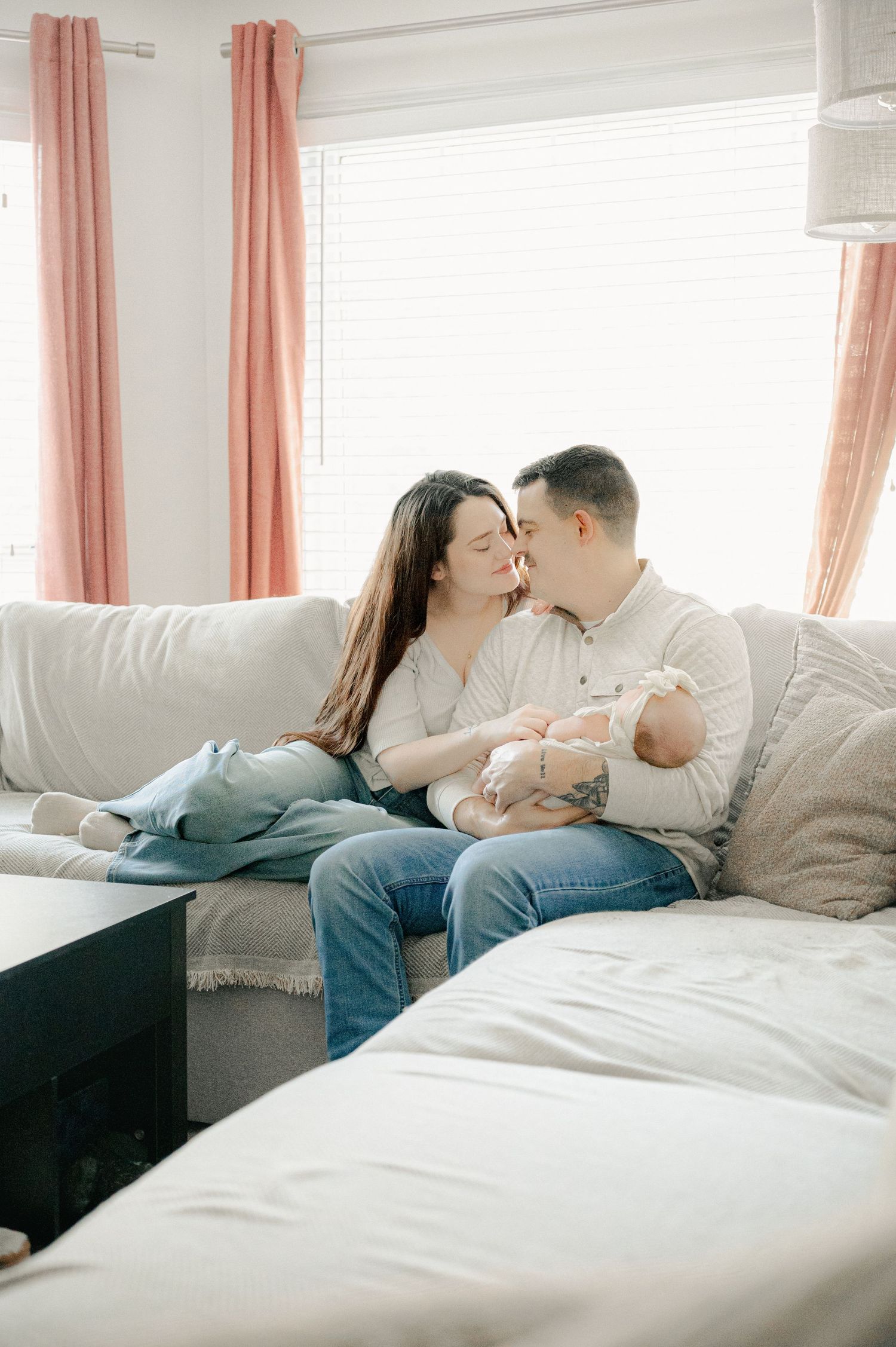Intimate family moment captured on comfortable sectional sofa near window.