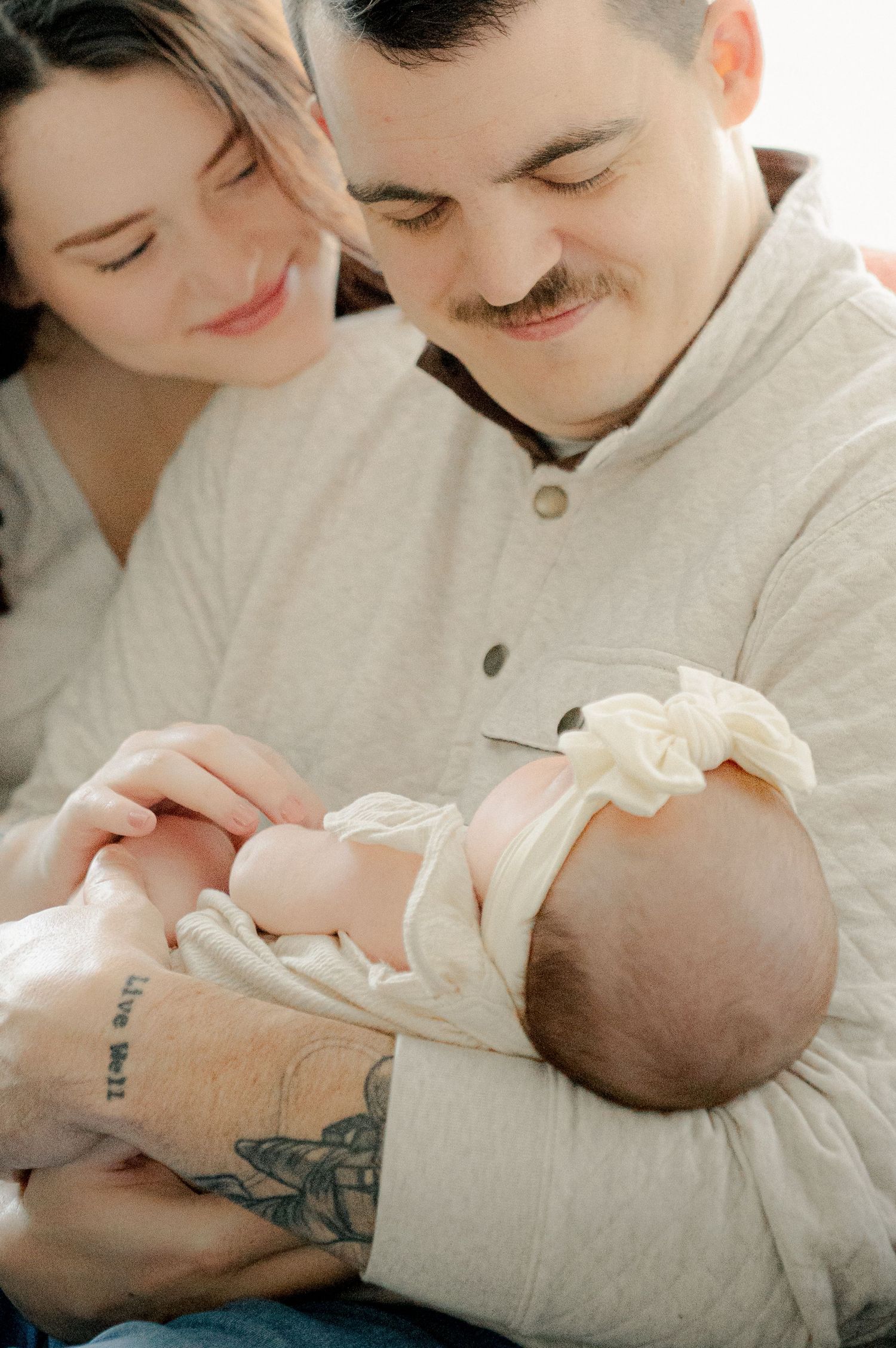 Intimate family portrait showing tender moment with newborn in natural light.