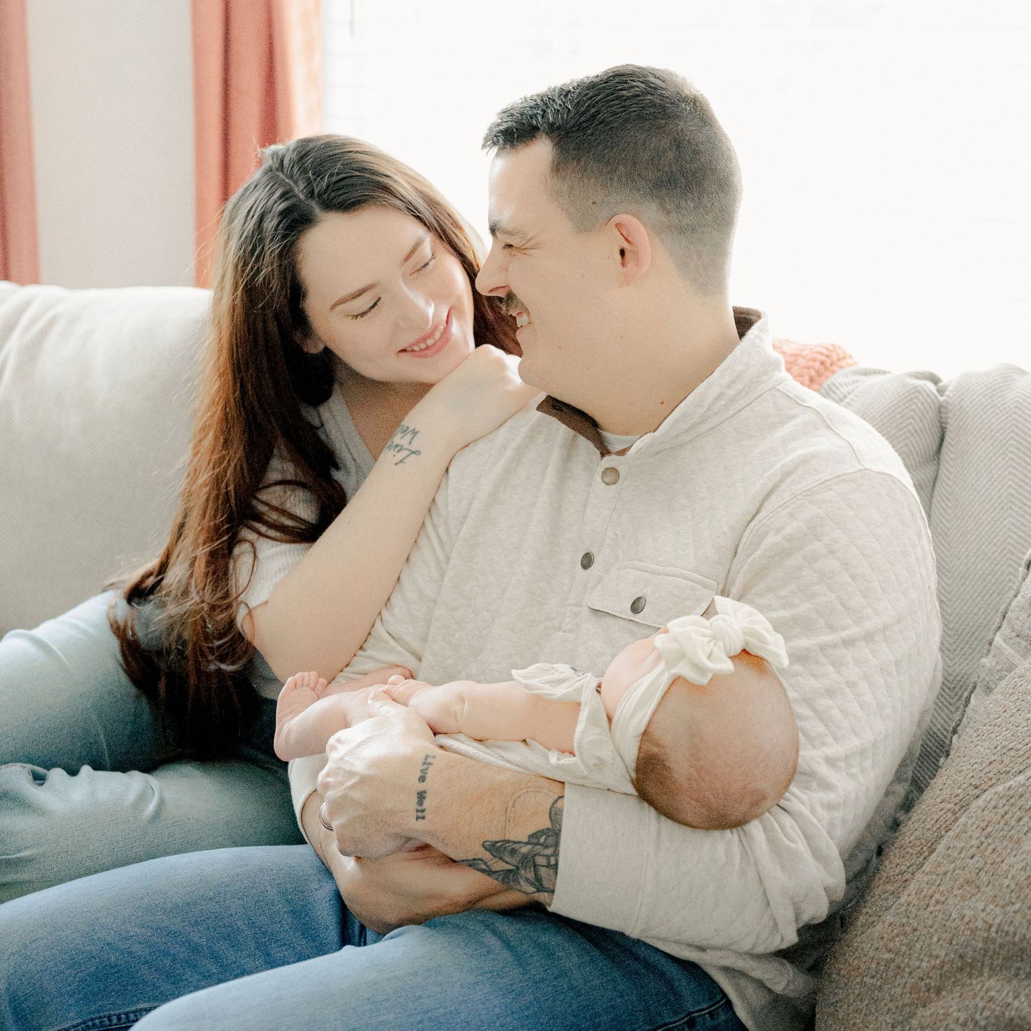 Tender family moment captured on grey sofa in bright living room.