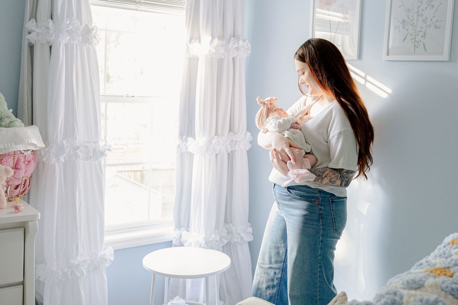 Gentle parenting scene by a bright window with white curtains.